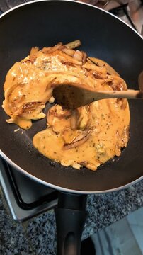 Healthy and nutritional lifestyle: Healthy breakfast preparation: fried brown onions with scrambled eggs being mixed on black cast iron wok