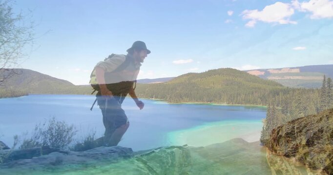 Hiker starting outcrop scanning terrain, leaping chasm navigating ridge with backpack for adventure