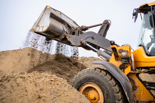 Front end loader dropping sand at construction site