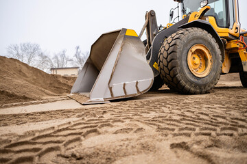 Front loader digging sand at construction site