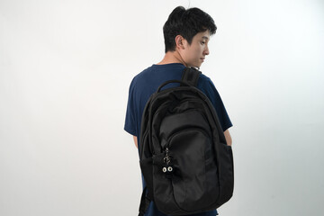 Fototapeta premium Side view of a young Asian man wearing a black backpack decorated with a small black handmade crochet cat for mockup or branding