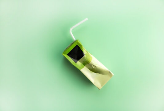 Top view of a crumpled green juice box on a green background