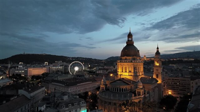 Aerial video about illuminated  St Stephens basilica at dusk. Hungarian Parlament's building is on the background
