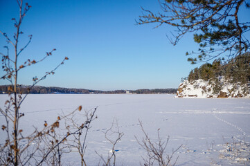 Lake landscape in winter. Calm winter view at the lakeshore.  Frozen lake, snow and trees. Calm and tranquil atmosphere.