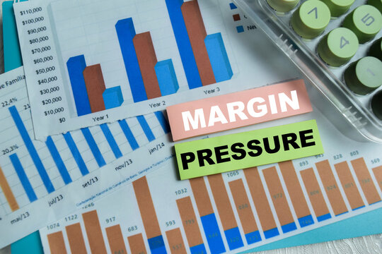 Concept of margin pressure write on sticky notes isolated on Wooden Table.