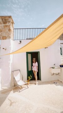 Woman relaxing on a sunlit terrace in southern Italy. Mediterranean climate, slow living atmosphere, warm light, summer calm, southern European lifestyle and peaceful holiday retreat concept