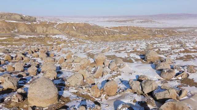 4K drone footage of clustered stone concretions of various sizes in the deserted winter Torish Valley of Stones, Mangystau, Kazakhstan. Aerial view of beige and brown low hills in the distance under