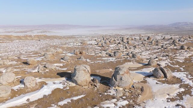 4K drone footage flying through scattered ancient stone concretions in the Torish Valley of Balls during a sunny winter day. Aerial landscape of unique geological formations in Mangystau, Kazakhstan, 