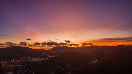 Fototapeta premium Aerial view of scenery Khao Rang viewpoint at twilight. view of a town nestled among lush green mountains at sunset, with a Pavilion structure perched on the hillside at Phuket town at Dusk