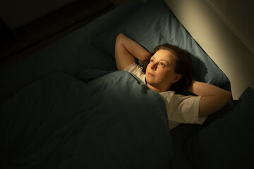 Obraz premium Brainstorming middle-aged woman with open eyes lying in bed, suffering from insomnia and sleep disorder