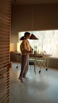 Woman dances into the frame inside a warm modern home in the mountains. Soft natural light, calm interior and relaxed movement create a cozy slow living atmosphere. Peaceful lifestyle and mindful home