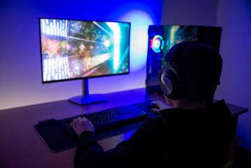 Gamer seen from behind using desktop pc with rgb lighting, emphasizing immersive gameplay,...