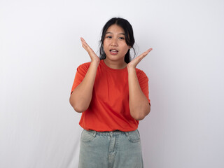 Beautiful young Asian girl in orange shirt with makeup pointing to copy space above isolated on white background.