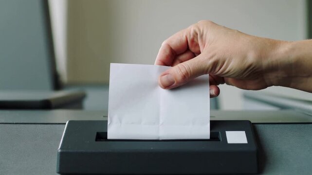 A persons hand inserts a document into a compact scanner on a desk, capturing the information digitally.