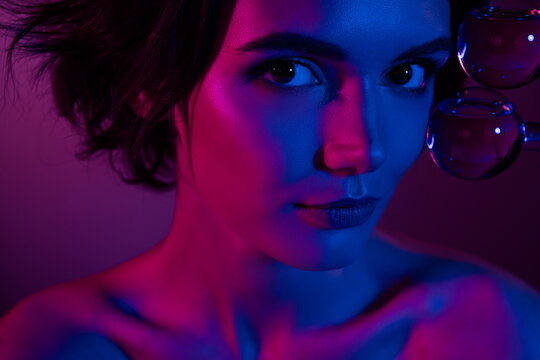 Photo of gorgeous young woman applying liquid beauty product in bottles on face rejuvenating skin cryo technology