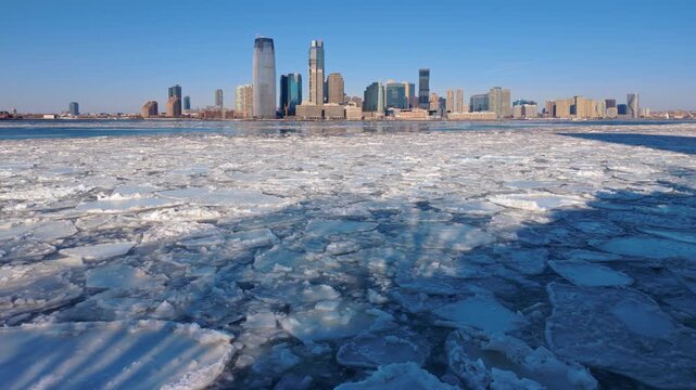 Drifting ice floes in frozen Hudson River. Downtown Jersey City skyline and waterfront during extreme winter cold