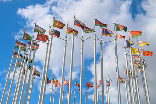 Group flags of different countries waving in wind on closed chain of flagpoles