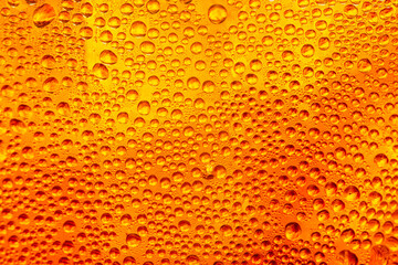 A macro image of water droplets clinging to a glass containing amber-colored cola liquid,Close-up macro shot of water droplets and condensation on a chilled glass filled with a refreshing amber. © banjongseal324