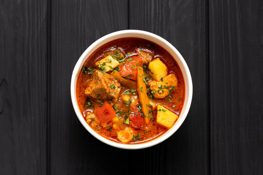 Hungarian bograch goulash soup with beef and vegetables in kraft bowl on dark wooden table