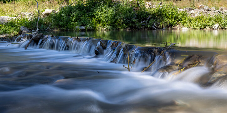 a calm river with a change in water level, a small waterfall, soft water
