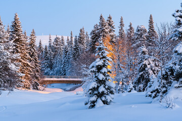 Frozen river with a road bridge surrounded by snow covered forest in Sweden during winter