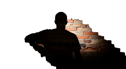 A man's silhouette standing beside a brick wall, casting a shadow