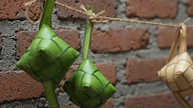 Ketupat Hanging on a String Against a Brick Wall Background.