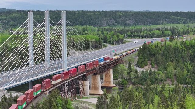 A freight train rolls through rural Canadian landscape - Aerial View