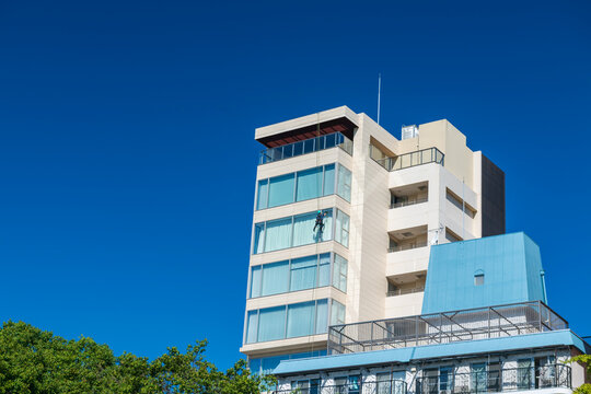Window cleaner man cleansing on high building against blue sky, Fukuoka