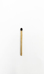 A single wooden matchstick with a dark brown sulfur head, centered vertically against a clean white background, symbolizing simplicity and potential energy