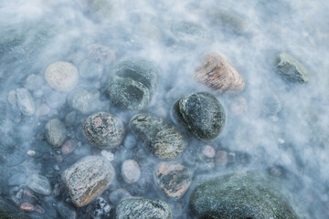 Stones covered by waves in the sea along the coast of Sweden on a cloudy day