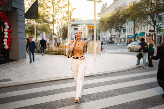 Happy young adult woman talking on phone in Vienna street