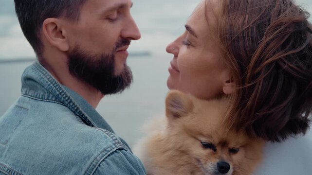 Affectionate family couple with a cute spitz dog enjoying a tender moment together outdoors