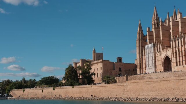 Historic Majorca landmarks, Almudaina Palace and Palma Cathedral La Seu stand majestically by the water on a sunny day.