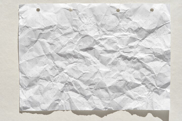 Crumpled white graph paper sheet with subtle dot pattern on neutral background.