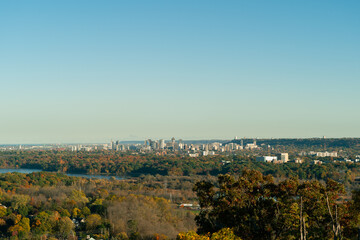Fototapeta premium Panoramic of Hamilton, Ontario in Canada, skyline rising above colorful autumn forest, capturing urban landscape surrounded by fall foliage.