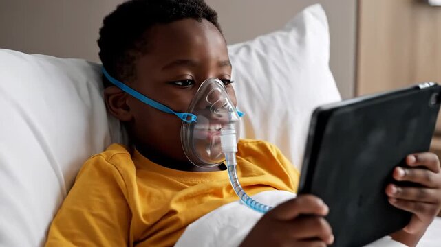Child patient with oxygen mask watching tablet in bed, focusing on recovery and entertainment