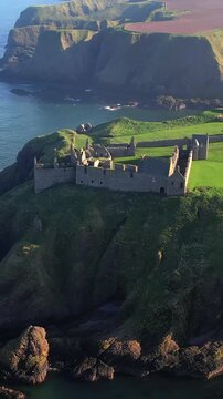 Aerial footage revealing the majestic Dunnottar Castle ruins perched on a cliff above the North Sea