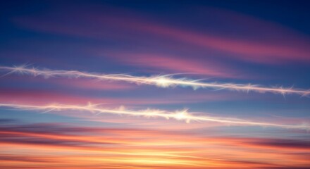 Obraz premium Vibrant sunset sky with contrails and sun