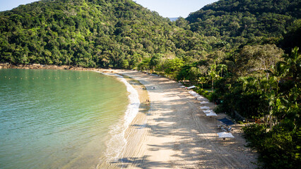 Aerial drone view of Domingas Dias Beach in Ubatuba, Brazil, showing clear water, preserved Atlantic forest and empty shoreline on a sunny morning. Tropical coastal landscape ideal for travel and natu © Guga Asciutti