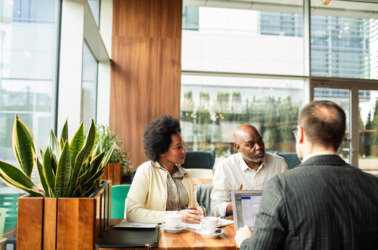 Mature couple meeting with financial advisor in modern cafe