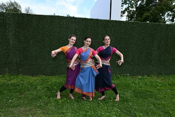 Three dancers in national costumes dance in the park on a summer day. Indian dance lessons, choreography.
