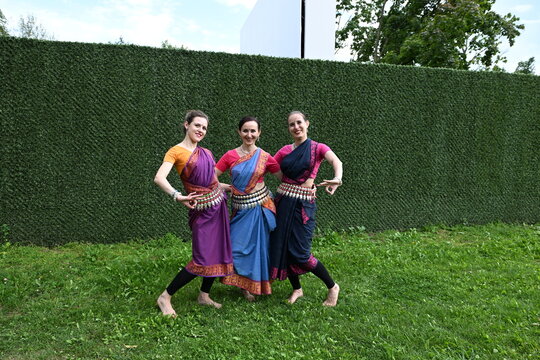 Three dancers in national costumes dance in the park on a summer day. Indian dance lessons, choreography.
