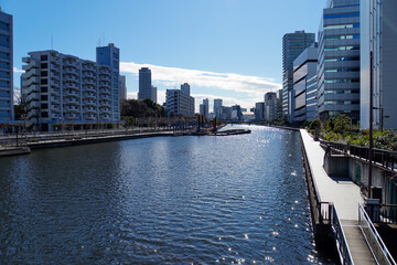 晴天の下でキラキラと光る水面が美しい都市部を流れる運河と両岸に並ぶビル群