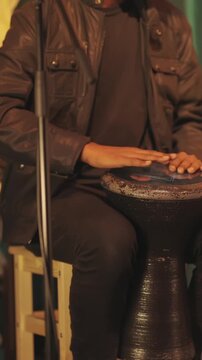 A musical group performs on stage in a bar - a man plays a bata instrument