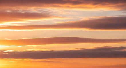 Dramatic sunrise over calm ocean horizon with golden clouds and warm orange sky reflection