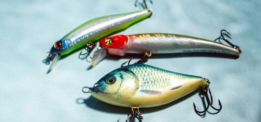 Colorful fishing lures and tackles on blue background with shadow from water, ready for fishing