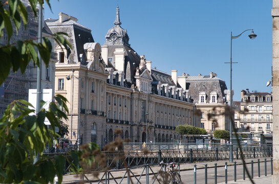 Rennes Classical Street and Bicycle View - View of elegant classical architecture in Rennes, France, featuring mansard roofs and a dome, framed by modern urban street furniture and foliage.