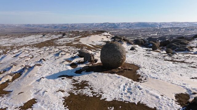4K drone footage close-up of a large stone concretion among a field of concretions in the Torish tract, Mangystau, Kazakhstan. Scenic winter landscape with sedimentary rocks, snow
