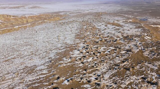 4K drone footage distant view of a vast valley covered with round stone concretions of various sizes, both whole and cracked, in Torish, Mangystau, Kazakhstan. Winter landscape with snow